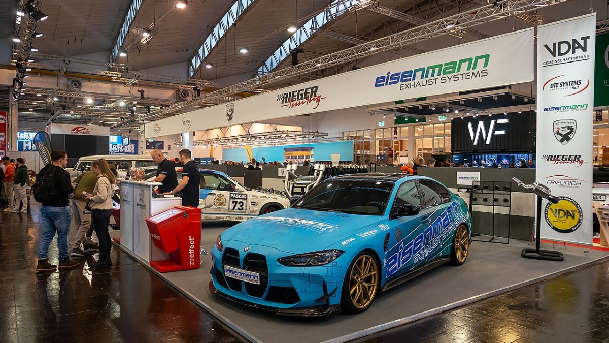 Pabellón de una feria automotriz con stands de empresas y un auto en exhibición