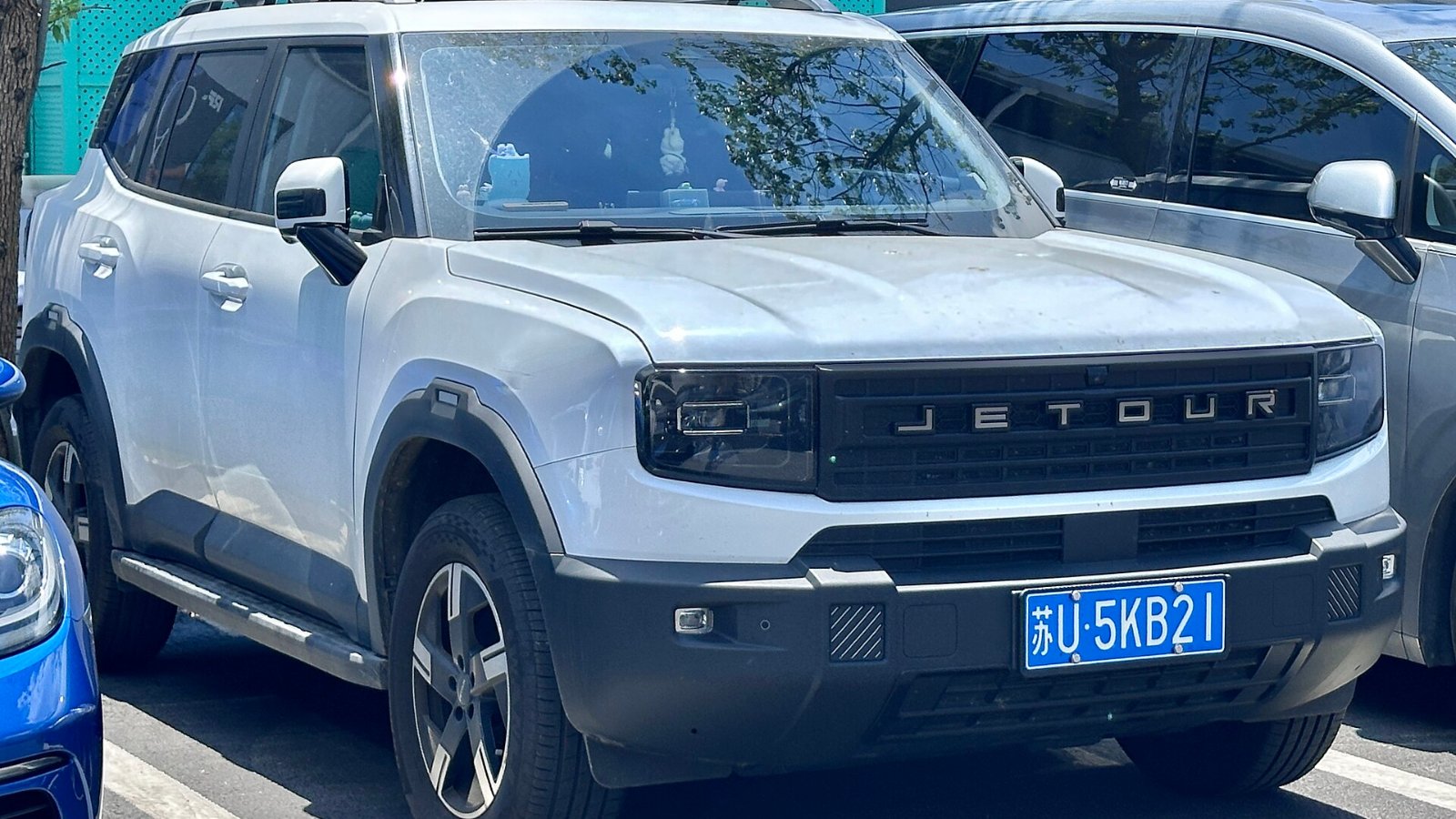 JETOUR 自由者 blanco con placa china estacionado frente a un club de tenis