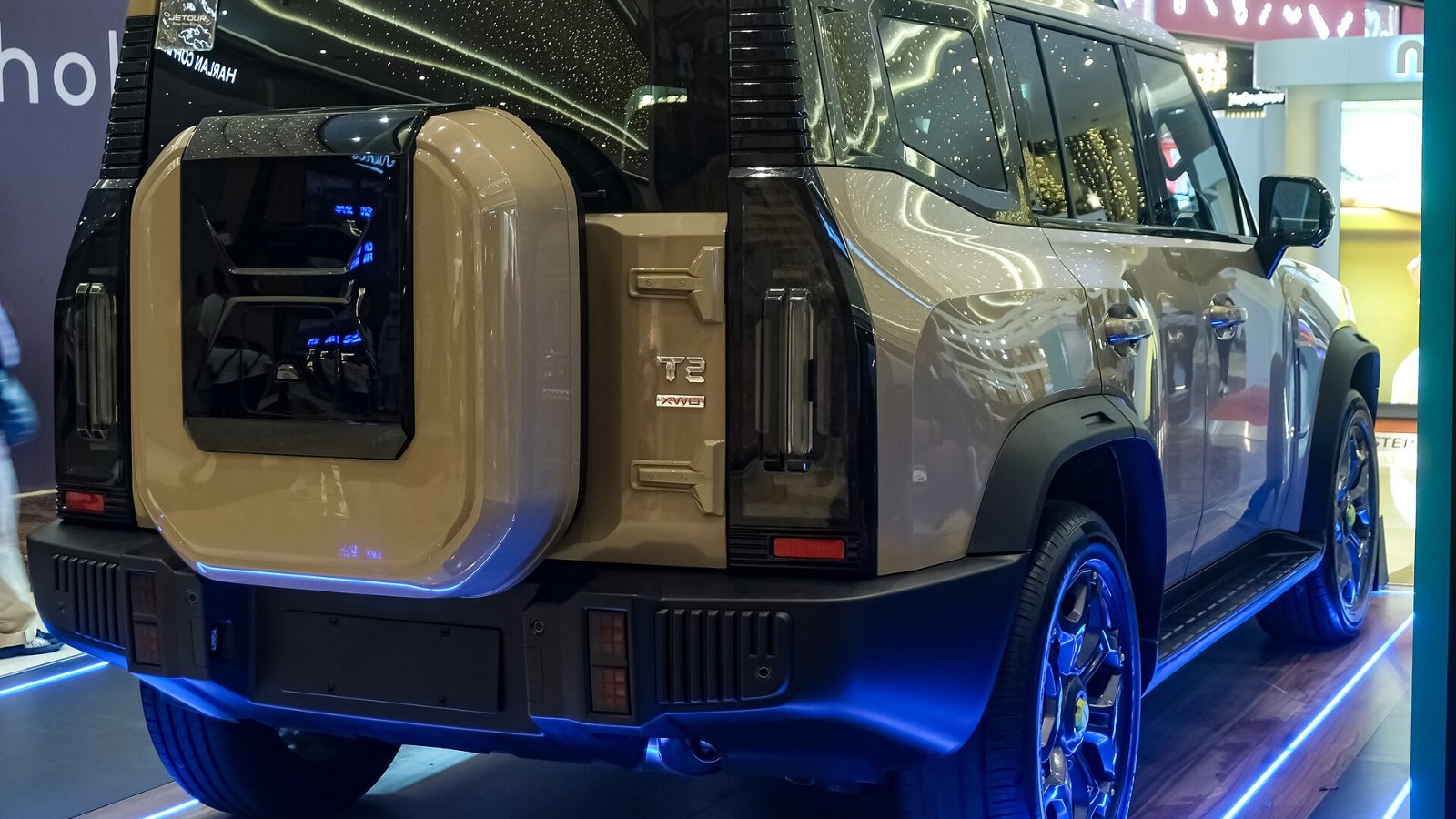 Vista trasera de un JETOUR T2 2.0T Beyond XWD color beige con la rueda de repuesto en el portón, en el centro comercial SM Aura